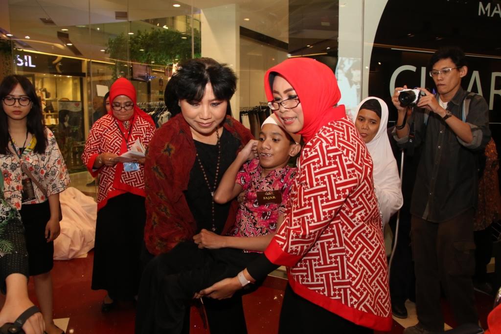 Ketua Umum BKOW Jatim Fatma Saifullah Yusuf bersama Anne Avante saat menggendong Fajar, salah satu difabel penerima kursi roda di aksi Berbagi Kasih yang diselenggarakan di Grand City Surabaya, Jumat (9/6).  (foto: humaspemprov)