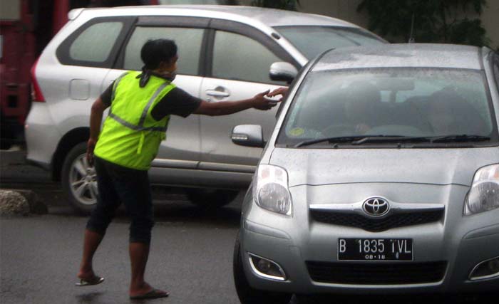 Seorang pembantu lali lintas sedang menerima uang dari pengemudi kendaraan di salah satu belokan di Jakarta. (foto: dokumentasi)