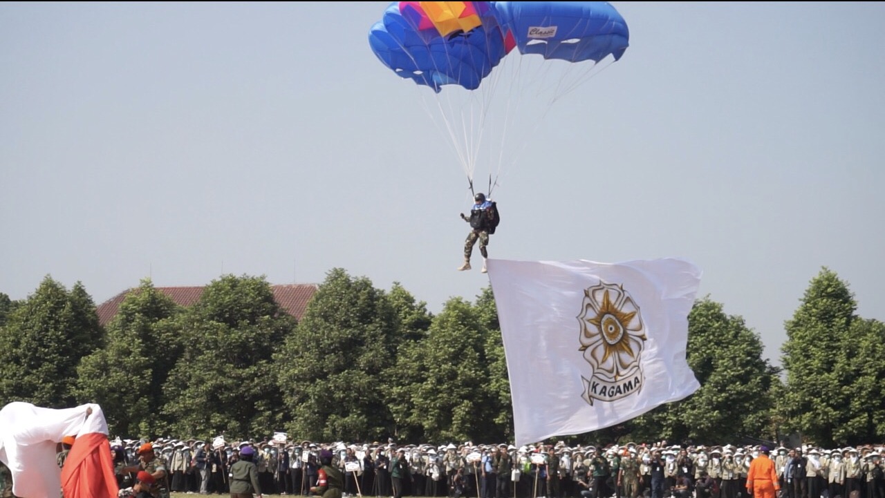 MAHASISWA BARU: Seorang penerjun dengan membawa bendera almamter sukses mendarat di tengah mahasiswa baru UGM. 