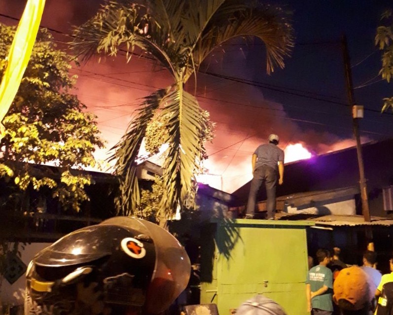 Warga mencoba memadamkan kobaran api yang melanda pemukiman warga di kawasan Jalan Tales, Bendul Merisi, Surabaya, pada Sabtu (12/8) malam. (Foto: Istimewa)