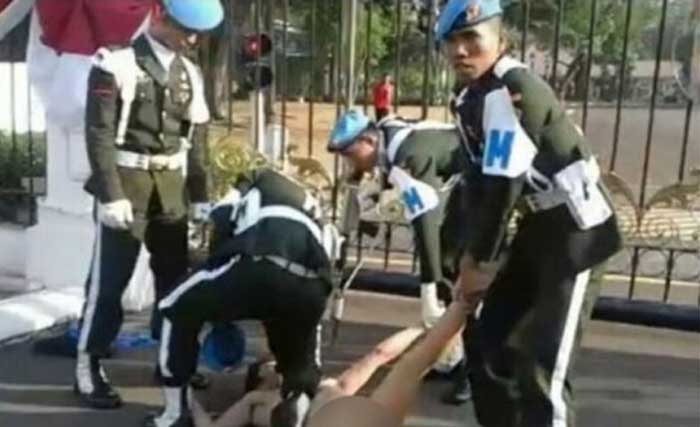 Seorang laki-laki bertelanjang yang diduga menderita gangguan jiwa dirungkuk Paspampres di depan Istana Merdeka, Jakarta, hari Senin (28/8) pagi. (foto: tribunmedan)