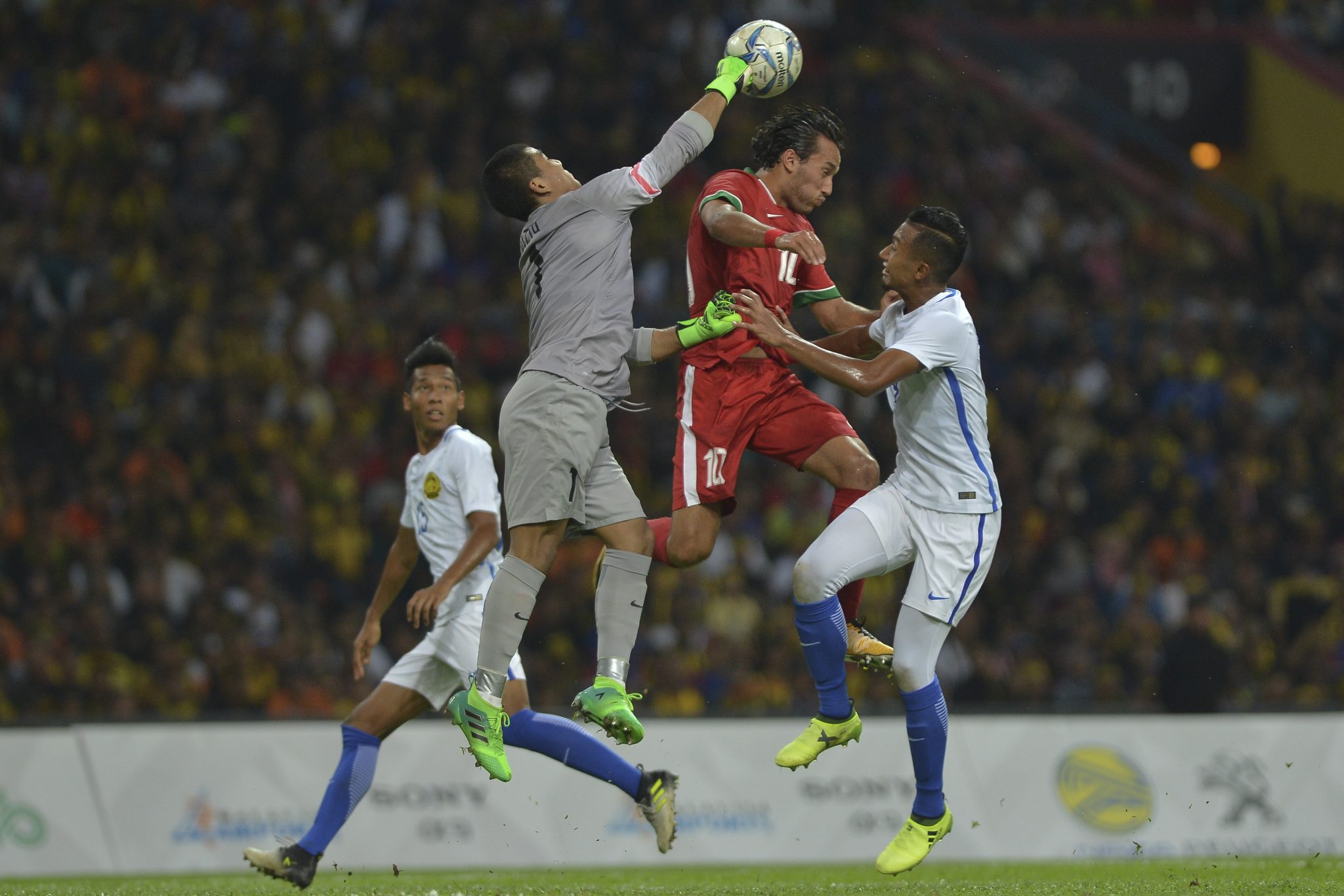 Kiper Timnas Malaysia, Haziq Nadzli  meninju bola saat berhadapan dengan Timnas Indonesia. Kali ini akibat tinjunya, Malaysia malah gagal meraih medali di cabor paling bergengsi ini.