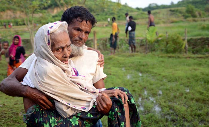  Foto yang diambil pada 30 Agustus 2017 ini menunjukkan seorang pria Rohingya membopong ibunya di Ukhiya setelah melewati perbatasan Bangladesh-Myanmar. Organisasi Imigrasi Internasional pada 30 Agustus mengatakan sedikitnya 18.500 warga menyeberang ke Bangladesh sejak pertempuran meletus di negara bagian Rakhine selama enam hari terakhir. (foto: suzauddin rubel/afp) 