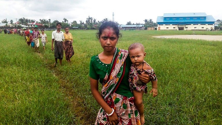 Seorang perempuan etnis Rohingya menggendong bayinya setelah tiba di kota Yathae Taung, Rakhine, Myanmar, setelah kabur dari desanya yang diserbu militer, (26/8). (Foto: Wai Moe/AFP)