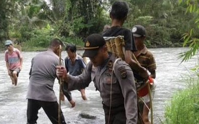 Kapolsek Bunta harus melewati sungai dengan menggendong warganya yang sedang sakit.