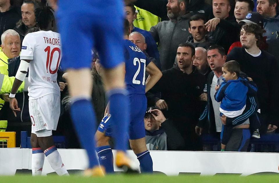 Seorang suporter Everton beberapa saat sebelum meninju pemain Lyon sambil mengendong anak kecil. 