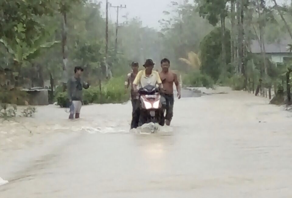 Pengendara motor berusaha menerjang banjir di Aceh Singkil. Foto : BNPB