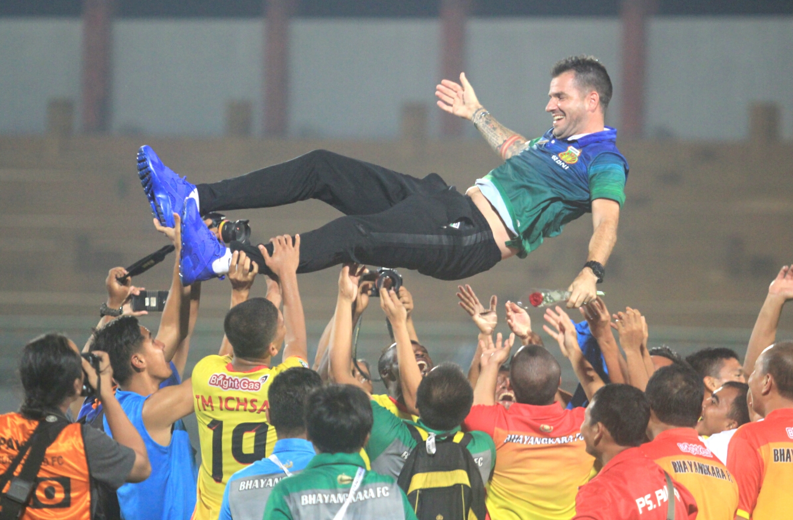 Pelatih Bhayangkara FC, Simon McManemey dilempar ke udara setelah memastikan timnya menjadi juara Liga 1 di Stadion Gelora Bangkalan, tadi malam. foto:ngopibareng.id/tom