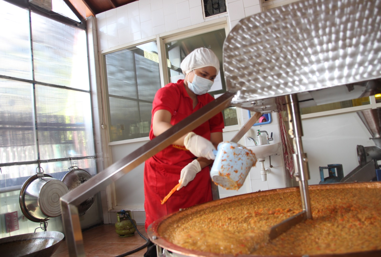 Salah satu pekerja, sedang mengolah Sambal Dede Satoe, di ruang produksi, di dalam rumah yang terletak di Jalan Tenggilis Timur VI, Surabaya. (Foto: farid/Ngopibareng.id)
