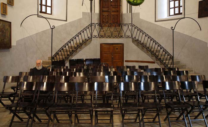 Seorang pendeta duduk di dalam gereja Nativity saat warga berukumpul merayakan Natal di kota Bethlehem, Palestina pada Minggu 24 Desember kemarin. (foto: hazem bader/afp)