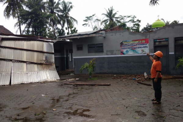 Petugas BPBD menujukkan kerusakan ruang kelas akibat diterjang angin puting beliung di SDN Pondokrejo 5, Kecamatan Tempurejo, Kabupaten Jember. (Foto: Antara)