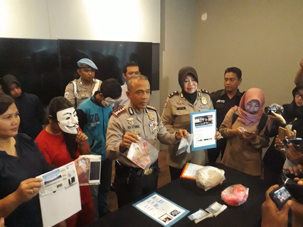 'VR' tersangka menggunakan Topeng bersama Mapolrestabes Surabaya, Rudi Setiawan menunjukan beberapa barang bukti berupa uang tunai dan handphone. (Foto: Istimewa)