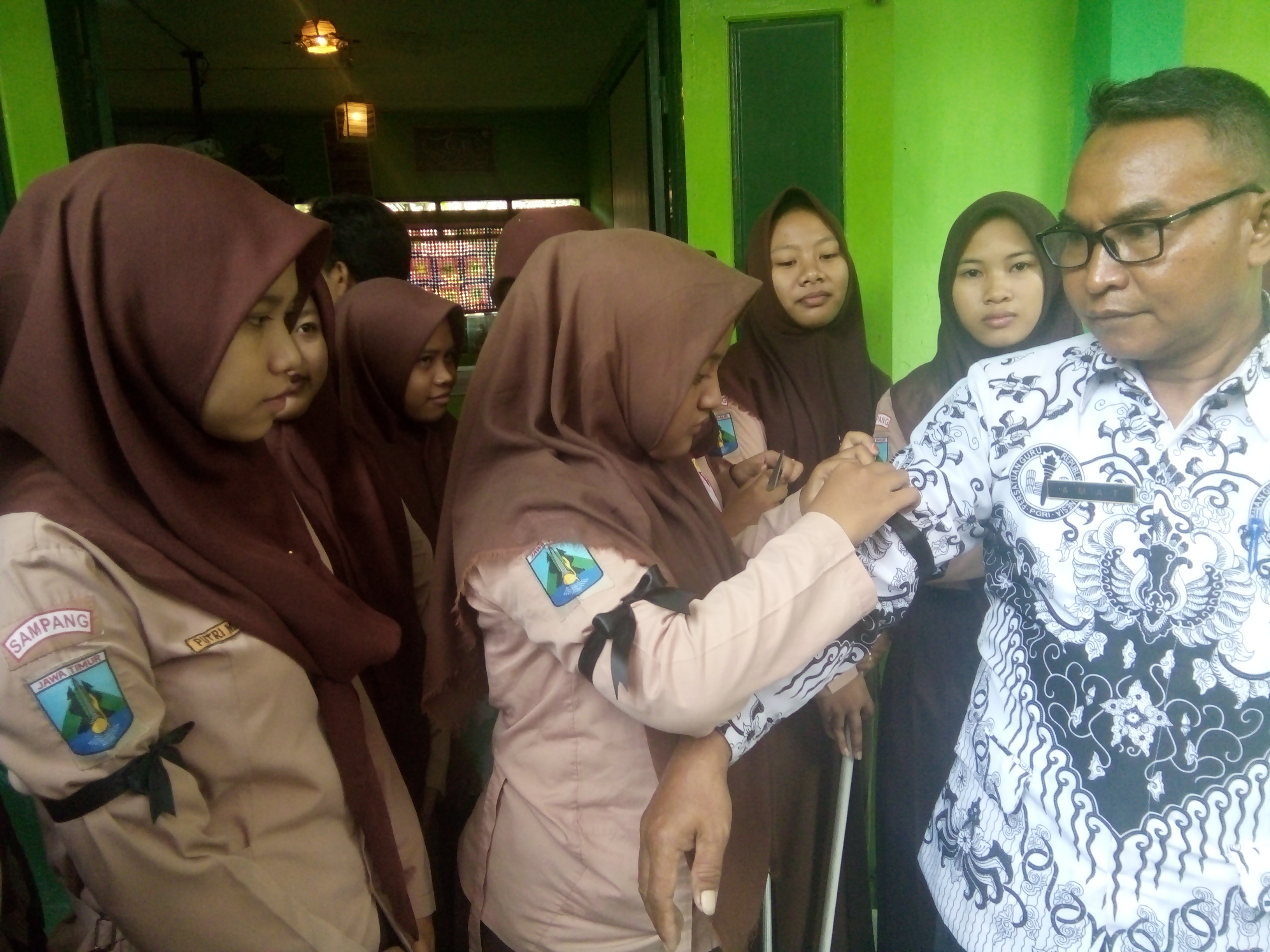 Amat, Kepala Sekolah SMA 1 Torjun dibantu siswa mengenakan pita hitam. foto:widikamidi