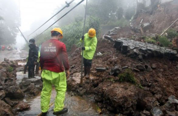 Petugas BPBD Kabupaten Bogor berusaha membersihkan material longsor yang menutupi jalur utama Puncak Bogor, Jawa Barat, Senin 5 Januari. Jalur Puncak, Bogor ditutup sementara akibat cuaca ekstrim yang mengakibatkan bencana longsor di empat titik di ruas jalan di Jalan Raya Puncak yaitu di seputaran Masjid Atta'awun, Riung Gunung, Grandhill, dan Widuri. (Foto: Antara)