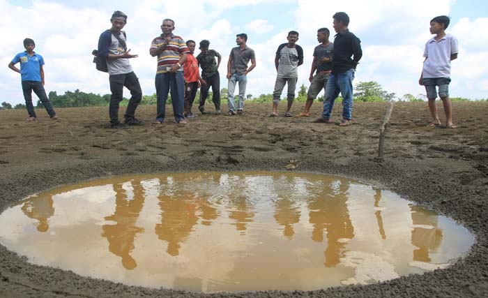 Sejumlah warga melihat gelembung gas yang bermunculan di area lahan di Desa Blang Seunong, Kecamatan Pante Bidari, Aceh Timur, hari Kamis 8 Februari 2018. (fotosyifa yulinnas/antara)