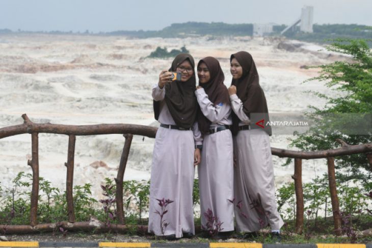 Pengunjung berswafoto dengan latar area pertambangan di Wisata Taman 'Bukit Daun' di Tuban, Jawa Timur, Kamis 22 Februari 2018. Tempat wisata yang dibangun di lahan bekas tambang batu kapur milik Semen Indonesia tersebut diharapkan menjadi wahana wisata baru bagi masyarakat. (Foto: Antara) 