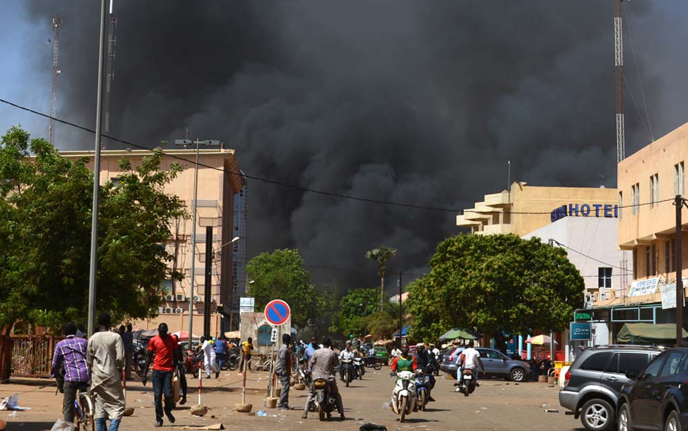 Warga melihat asap hitam membubung saat ibu kota Burkina Faso dihujani beberapa serangan pada 2 Maret yang menargetkan kedutaan besar Prancis, pusat kebudayaan Prancis dan markas militer negara tersebut. Saksi mengatakan lima orang keluar dari mobil dan menembaki orang-orang di kedutaan. Saksi lain mengatakan ada ledakan di dekat markas tentara Burkina yang terletak satu kilometer dari lokasi pertama. (foto: afp/ahmed ouoba)