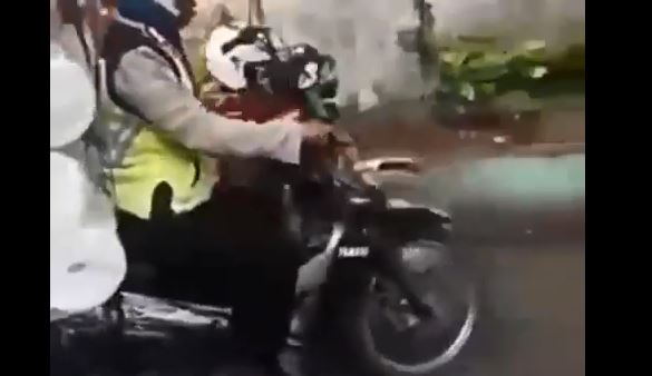 Tangkapan layar, polisi yang bawa tumpukan gulungan kain. (Foto: Youtube).