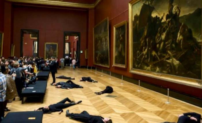 Para pengunjuk rasa berbaring di lantai di depan  lukisan dari abad ke-19 karya Theodore Gericault berjudul “The Raft of the Medusa,” di Museum Louvre, Paris hari Senin 12 Maret 2018. (foto:afp)
