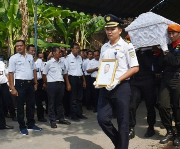 Sejumlah petugas mengusung peti jenazah Mustofa masinis Kereta Api (KA) Sancaka yang tewas kecelakaan, dari rumah duka untuk dimakamkan di Desa Sumberbening, Balerejo, Kabupaten Madiun, Jawa Timur, Sabtu 7 April 2018. Mustofa tewas akibat KA yang dimasinisi bertabrakan dengan truk tronton di antara Stasiun KA Kedungbanteng-Walikukun Ngawi, Jawa Timur, Jumat 6 April 2018 dimakamkan di pemakaman umum Desa Sumberbening. (Foto: Antara)