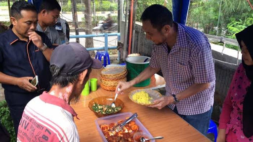 Jusuf Hamka saat melayani pembeli nasi kuning dagananya. (Foto: tribunnews)