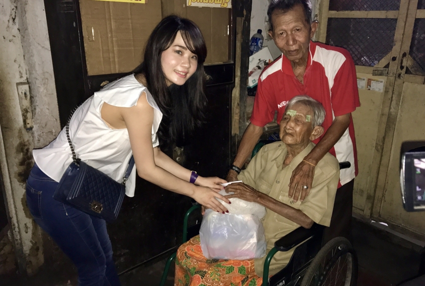 Seorang gadis keturunan Cina memberikan santunan kepada salah satu penghuni Gedung Setan. Para penghuni gedung tua yang menjadi cagar budaya ini hidup dengan pas-pasan. Tetapi hidupnya rukun dan damai. (Foto: Bahari)