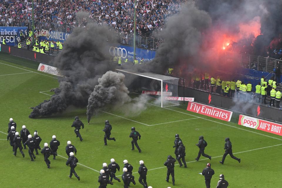 Suporter Hamburg melempar bom asap ke dalam lapangan usai laga. foto:reuters