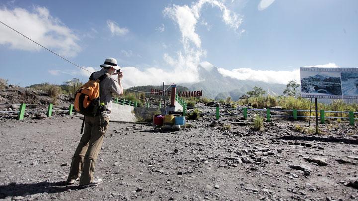 Wisatawan mengabadikan Gunung Merapi dari kawasan wisata Bungker Kaliadem, Sleman, DI Yogyakarta, 22 Mei 2018. Pasca naiknya status Gunung Merapi dari normal menjadi waspada, wisata di kawasan Kaliadem yang menjadi salah satu destinasi wisata andalan di Sleman itu sepi pengunjung. (Foto: Antara)