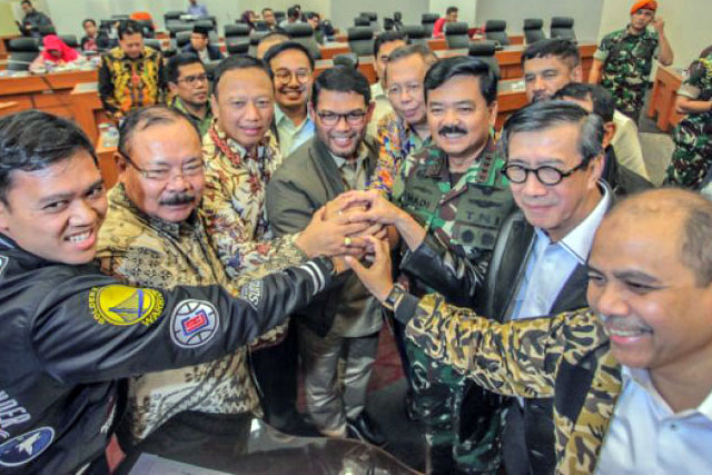 Menkumham Yasonna Laoly (kedua kanan) berjabat tangan bersama Panglima TNI Marsekal Hadi Tjahjanto (ketiga kanan) dan sejumlah anggota Pansus Terorisme DPR usai ditandatanganinya hasil revisi UU Anti-Terorisme di Kompleks Parlemen Senayan, Jakarta, Kamis, 24 Mei 2018).  (Foto: Antara)