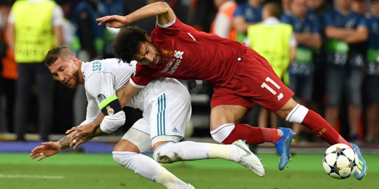 Striker Liverpool, Mohamed Salah (kanan), kehilangan keseimbangan saat dijaga ketat oleh bek Real Madrid, Sergio Ramos, dalam laga final Liga Champions di Stadion NSC Olimpiyskiy, Kiev, Ukraina pada 26 Mei 2018. (Foto: AFP)