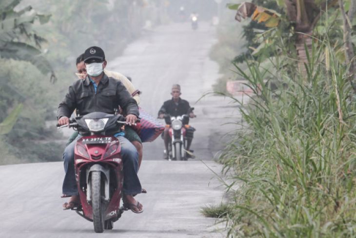 Warga melintasi jalan yang diselimuti abu vulkanik letusan Gunung Merapi di Muntilan, Jawa Tengah. (Foto: Antara)