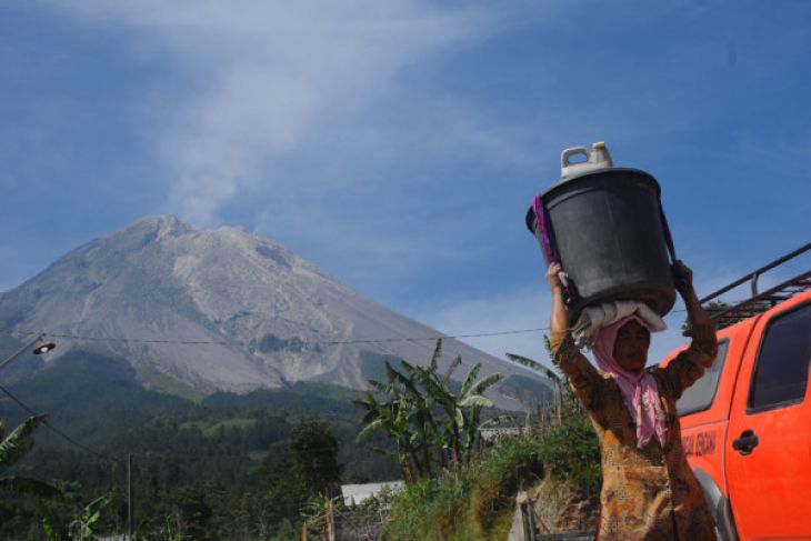 Warga memanggul ember berisi air di Stabelan, Tlogolele, Selo, Boyolali, Jawa Tengah, Sabtu 2 Juni 2018. Warga lereng Gunung Merapi yang sempat mengungsi, kembali menjalani aktivitas pagi mereka pascaletusan Gunung Merapi pada Jumat 1 Juni 2018. (Foto: Antara)