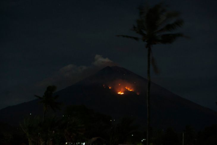 Api membakar hutan lereng Gunung Agung setelah terjadinya lontaran batu pijar dari kawah terlihat dari Desa Culik, Karangasem, Bali, Selasa 3 Juli 2018. Pusat Vulkanologi dan Mitigasi Bencana Geologi mencatat terjadinya erupsi Gunung Agung dengan tinggi kolom abu mencapai 2.000 meter yang disertai lontaran batu pijar sejauh dua kilometer. (Foto: Antara)