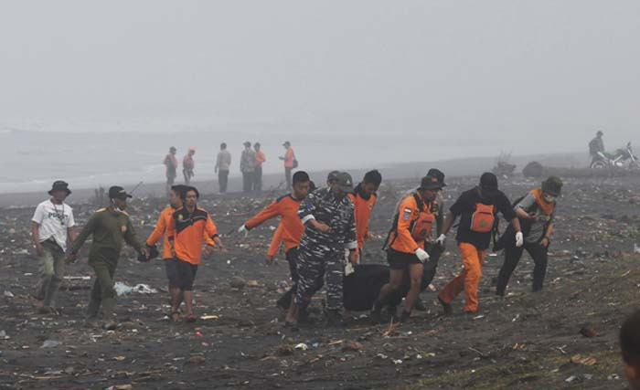 Anggota Basarnas beserta warga mengangkut jenazah korban kapal tenggelam yang ditemukan di bibir pantai di perairan Plawangan Puger, Jember, Jawa Timur, Jumat, 20 Juli 2018. Sebanyak 22 nelayan menjadi korban dalam kejadian tersebut, 12 diantaranya selamat dan 8 nelayan tewas serta dua orang masih dalam pencariaan. (foto: ANTARA FOTO/Zabur Karuru/ama/18) 