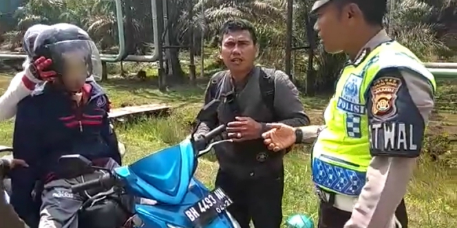 Anggota Kepolisian lalu lintas Polresta Tanjung Jabung Timur yang berpatroli menghentikan pengendara motor bonceng tiga, Senin 23 Juli 2018.