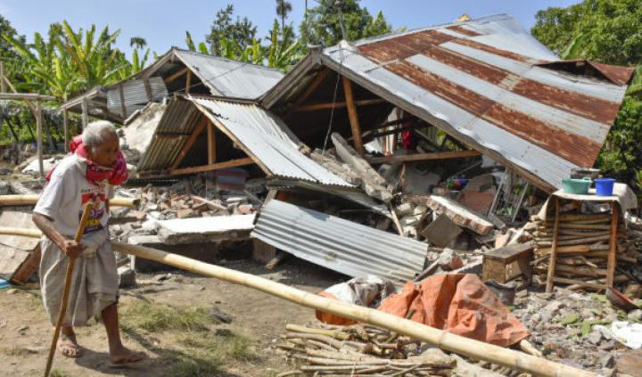 Warga berjalan di depan rumah yang roboh akibat gempa di Desa Sajang, Kecamatan Sembalun, Selong, Lombok Timur, NTB, Minggu 29 Juli 2018. Data sementara BPBD Provinsi Nusa Tenggara Barat mencatat, gempa bumi berkekuatan 6,4 skala richter (SR) mengakibatkan delapan orang meninggal dunia, 10 orang luka berat, 10 orang luka ringan, dan puluhan rumah rusak di Kabupaten Lombok Timur. (Foto: Antara)