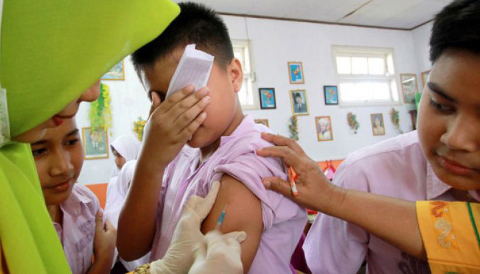 Seorang siswa mengintip diberikan imunisasi campak dan rubella (MR) di SD Negeri 61 Kota Gorontalo, Gorontalo, Kamis 2 Agustus 2018. Pemerintah Kota Gorontalo akan melakukan imunisasi MR kepada 53.650 anak usia 9-15 tahun dan membuka 476 pos pelayanan. (Foto: Antara)