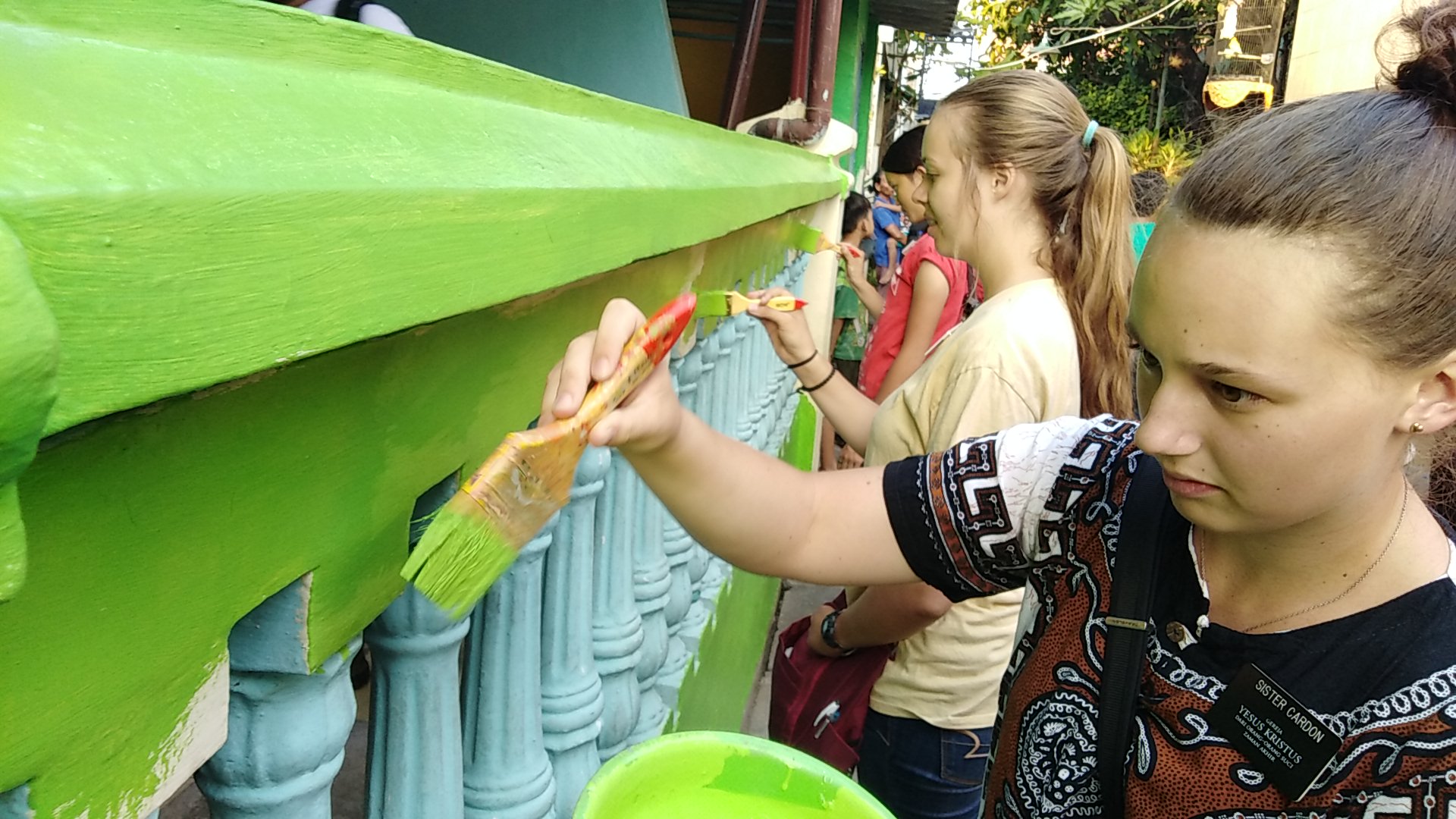 Wisatawan mancanegara tururt mengecat kawasan eks lokalisasi Dolly, Putat Jaya, Surabaya, Jumat, 3 Agustus 2018. (Foto: Farid/ngopibareng.id) 