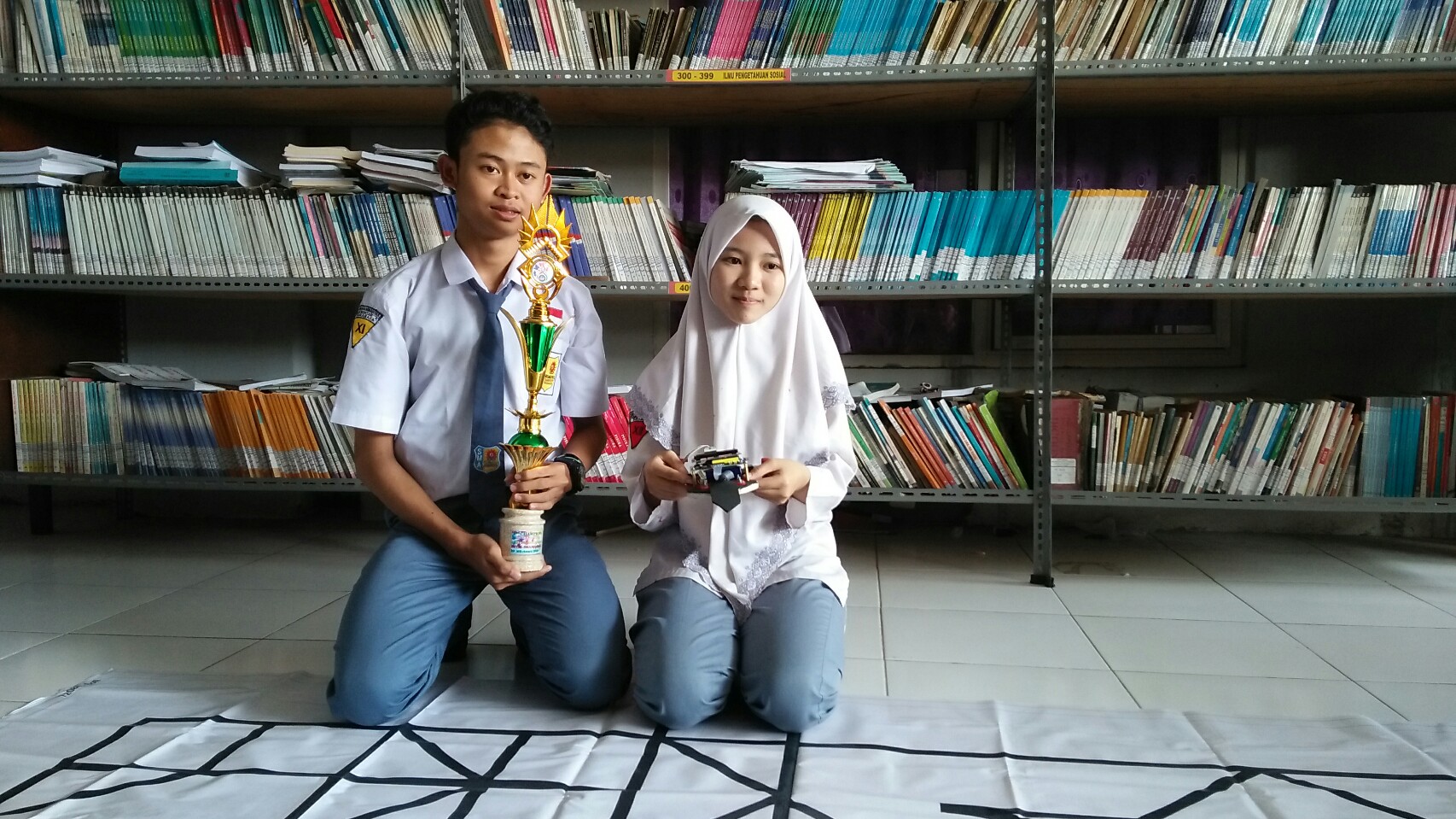 Shoffiah dan Farhan menunjukkan robot serta piala ketika mengikuti ajang Muhammadiyah Education Award. (Amanah/ngopibareng.id)