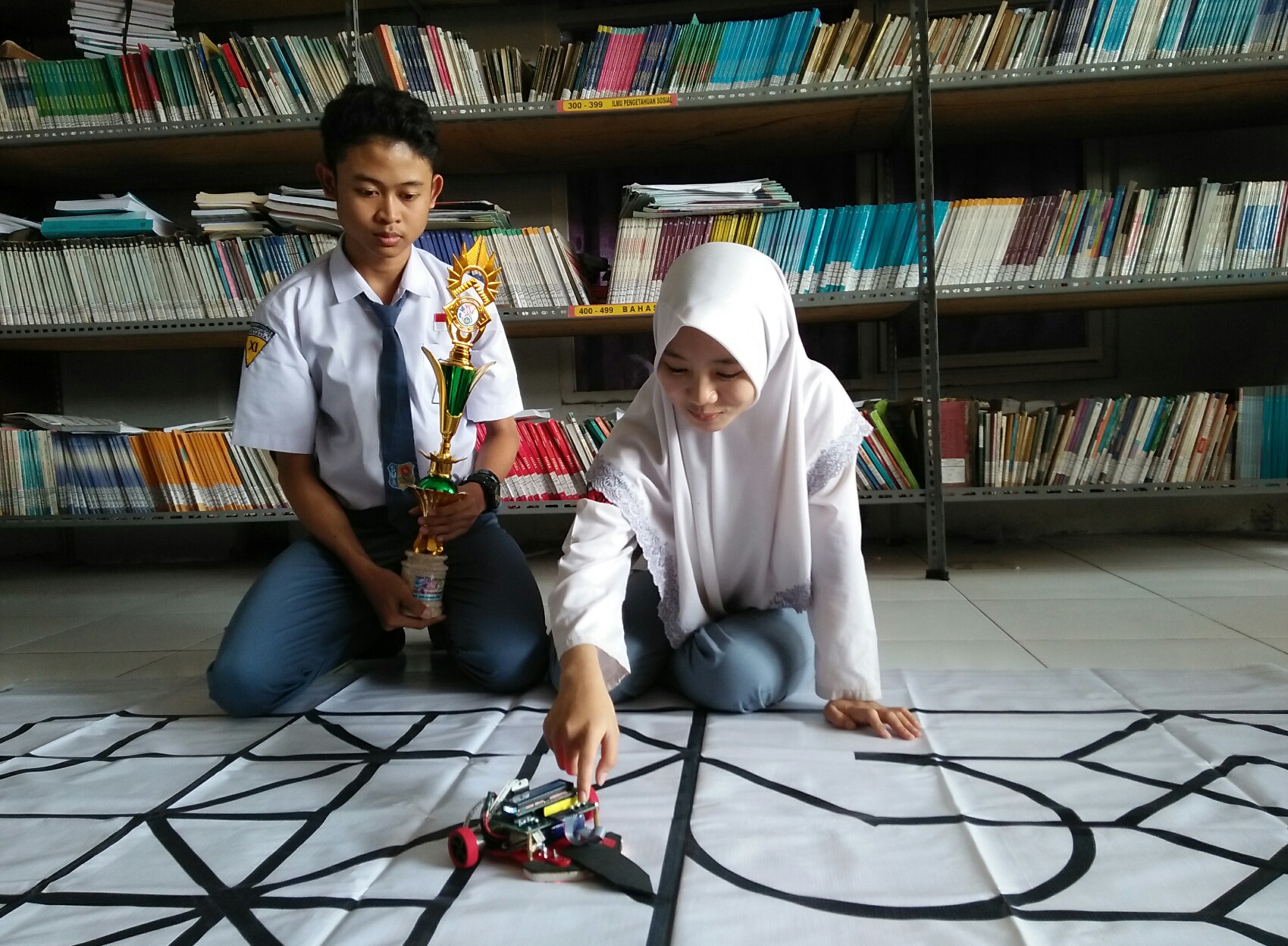 Shoffiah dan Farhan melakukan uji coba pada robot buatan mereka. (Amanah/ngopibareng.id)