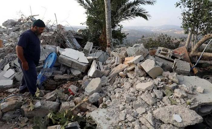 Seorang warga berdiri di atas puing-puing bangunan rumah Dar Youssef di Desa Kobar, sebelah utara Ramallah, Palestina, Selasa 28 Agustus kemarin. (Foto: AFP)