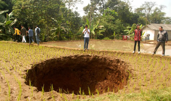  Warga melihat tanah amblas di lahan persawahan Kampung Legoknyenang, Desa Sukamaju, Kecamatan Kadudampit, Sukabumi, Jawa Barat, Jumat 7 September.. Di bawah lokasi tanah amblas itu terdapat lintasan aliran air selokan bawah tanah. (Foto: Antara/Budiyanto)