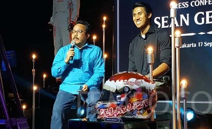 Sean Gelael (kanan) dan helm yang dilelang hari Senin malam 17 September 2018. (Foto: Tempo.co)