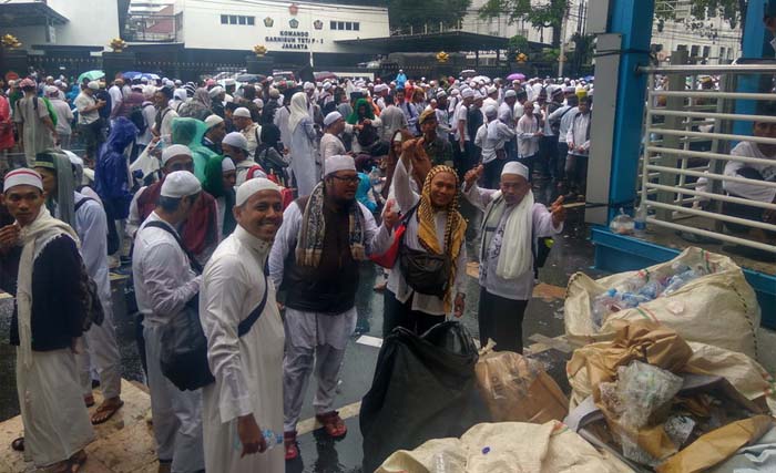 Peserta Reuni Damai Alumni 212 membersihkan sampah di kawasan sekitar Monas, Minggu 2 Desember 2018. (Foto:Okezone)