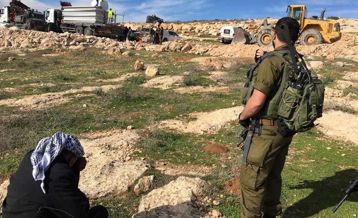 Dijaga serdadu Israel, seorang lelaki Palestina menunduk sedih  menyaksikan gedung sekolah At-Tahadi 12 di Kota Al-Khalil, bagian selatan Tepi Barat, hari Rabu pekan lalu. (Foto: News Network)