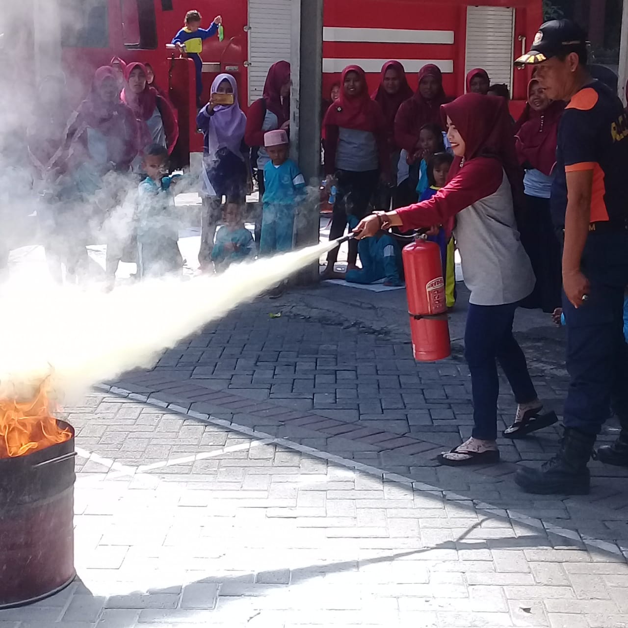 SIMULASI: Seorang guru saat mempraktikkan pemadaman api di kantor PMK Lamongan (Foto :Totok/ngopibareng.id)