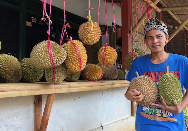 Mas Agung di depan rumah dan kebunnya yang jadi tempat wisata belah duren di Kesambon-Malang. (Foto Arif Afandi/ngopibareng)