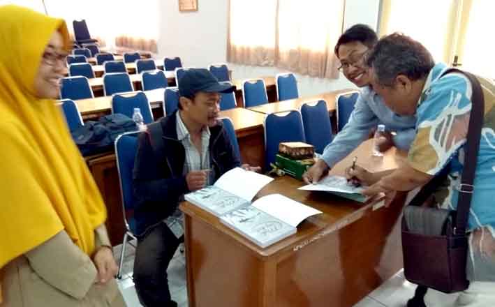 Dua editor buku Mider ing Rat, Budi Sarjono (kanan) dan R Toto Sugiharto (duduk) menandatangani buku-buku milik hadirin.