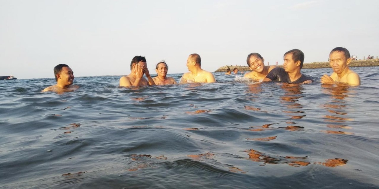 Sejumlah warga sedang berendam di laut di kawasan Pelabuhan Perikanan Mayangan, Kota Probolinggo. (Foto: Ikhsan/ngopibareng.id)