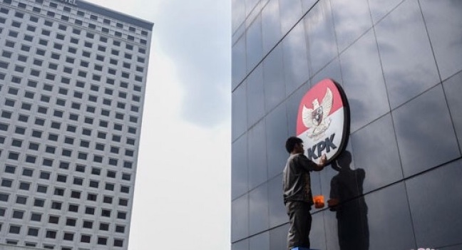 Seorang petugas membersihkan logo di Gedung KPK. (Foto: dok/antara)